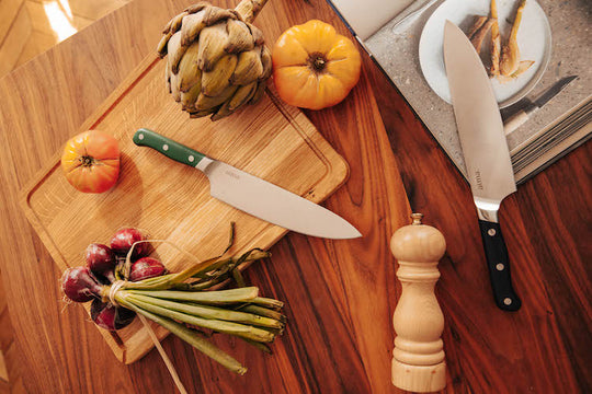 Cuchillo de cocina sobre tabla de madera y recetas